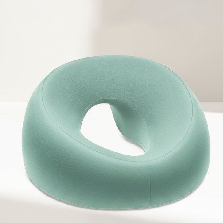 Green donut-shaped memory foam pillow on a white background