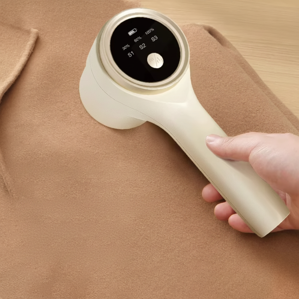 Hairball trimmer held by a hand on a brown fabric background with text highlighting features.